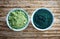 Bowl of spirulina algae powder and wheat sprout powder on wooden