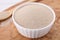 Bowl and spoon with active dry yeast on wooden board, closeup