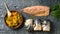 A bowl of steamed vegetables, the carcass of the mackerel and the three prepared loaf fish for baking. Flat lay.