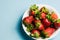 Bowl of strawberries on blue background