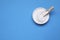 Bowl of sweet powdered fructose on light blue background, top view. Space for text
