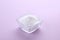 Bowl of sweet powdered fructose on light purple background