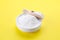 Bowl of sweet powdered fructose on yellow background