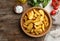 Bowl with tasty baked potato wedges on wooden background, top view