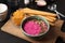 Bowl with tasty beet hummus, bread sticks and chips