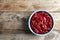 Bowl of tasty cranberry sauce on wooden background, top view.