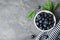 Bowl of tasty fresh blueberries, leaves and fabric on grey stone surface, flat lay