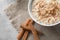Bowl with tasty oatmeal and cinnamon on grey background