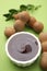 Bowl of tasty tamarind sauce and fresh pods on light green table