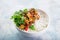 Bowl of teriyaki tofu cheese and rice served with lime, cilantro and sesame seeds