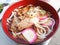 A bowl of udon noodles topped with sliced pork and KAMABOKO