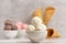 Bowl of vanilla, chocolate and pink berries ice cream and waffle cones on light background. Side view