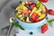 Bowl of vegetarian fresh fruit salad of different fruits: banana, kiwi, apple, orange, strawberry, blueberry on a blue