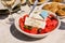 A bowl of village greek salad with greek flag on next to zucchini balls plate and white wine, water glasses served in