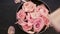 Bowl with water and pink roses and roses petals fall down top view wooden background, hand and nails spa concept