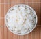 bowl of white steamed rice on bamboo mat.