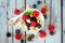 Bowl of yogurt with healthy fresh berries and granola, close up top view over blue wood