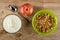 Bowl with yogurt, spoon, apple, bowl with granola on table. Top view