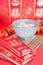 A bowl of Yuanxiao and hongbao in red background. The Chinese characters in the picture mean `happiness` and `good luck`