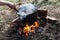 Bowler hat with dinner being prepared. hangs over a campfire on a summer evening