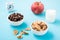 Bowls with cereal and chocolate balls, a glass of milk, an apple and an alarm clock on a blue background. Scheduled breakfast