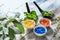 Bowls with color capsules and fresh herbs on wooden table