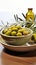 Bowls containing olives and adorned with rustic olive branch twigs on white