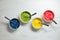 Bowls of different cream with food coloring on white marble table, flat lay