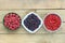 Bowls with fresh garden and forest berries: raspberry, purple shadberry, red currant overhead
