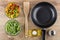 Bowls with frozen vegetables, spatula, frying pan, oil and salt