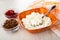 Bowls with jam and raisin, spoon in bowl with grained cottage cheese, napkin on wooden table