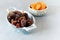 Bowls with juicy dates on a branch and dried apricots on a gray-blue background. Healthy tasty food