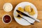 Bowls with mayonnaise and ketchup, plate with whole fried pancake roll, halves of pancake with meat, fork, knife on table. Top