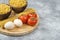 Bowls of raw pasta, eggs and fresh tomatoes on marble surface