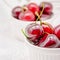 Bowls with red ripe sweet cherries with water drops on white background