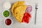 Bowls with scallion, mayonnaise, ketchup, fried cheburek, sweet peppers, onion in dish, fork on table. Top view