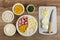 Bowls with sweet corn, rice, mayonnaise, parsley, eggs in saucer, ingredients of salad in plate, knife, chopped egg on cutting