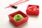 Bowls with swirl of wasabi paste and pickled ginger on white table, closeup