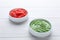 Bowls with swirl of wasabi paste and pickled ginger on white wooden table, closeup