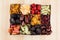 Box with assortment of dried fruits closeup on beige wooden background.