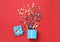 Box with bright confetti on red background, flat lay