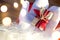 A box with a Christmas gift in the hands of Santa Claus in white mittens. Red suit, beard, garland lights in a blur. New year, pre