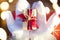 A box with a Christmas gift in the hands of Santa Claus in white mittens. Red suit, beard, garland lights in a blur. New year, pre