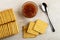 Box with crackers, bowl with apple jam, spoon, cookies on wooden table. Top view