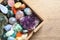 Box with different beautiful gemstones on wooden table