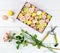 Box with flowers and macaroons, scissors on light wooden background, top view. Workplace of florist, concept of happy and