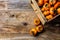 Box of fresh fruits persimmon kaki on wooden background. Copy space