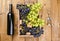 Box with grapes, a bottle of wine, a corkscrew, on a wooden background. View from above. Winemaking and harvesting