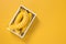 Box of ripe bananas on vivid yellow background