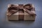 Boxed gift with brown bow on grey background top view celebratio